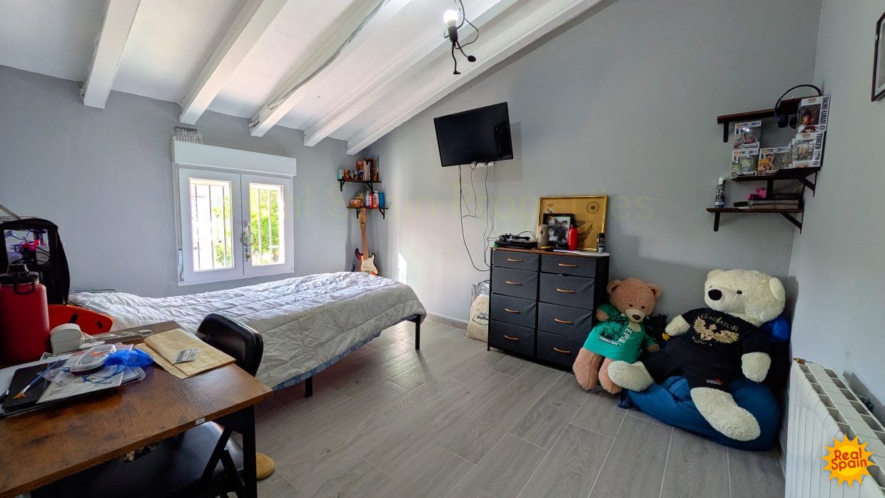 Bedroom at Cortijo Salud with bed, desk, television and exposed ceiling beams