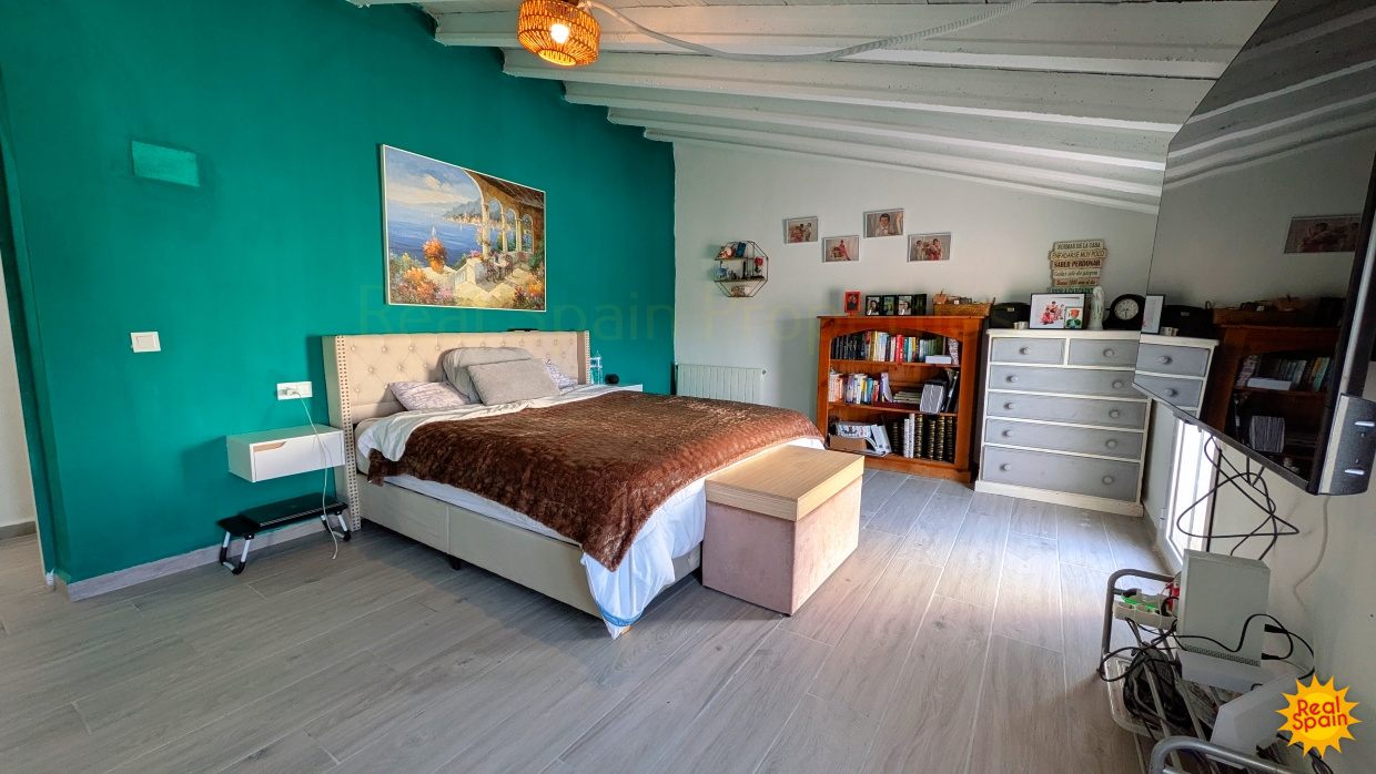 Large bedroom at Cortijo Salud with turquoise feature wall and storage furniture