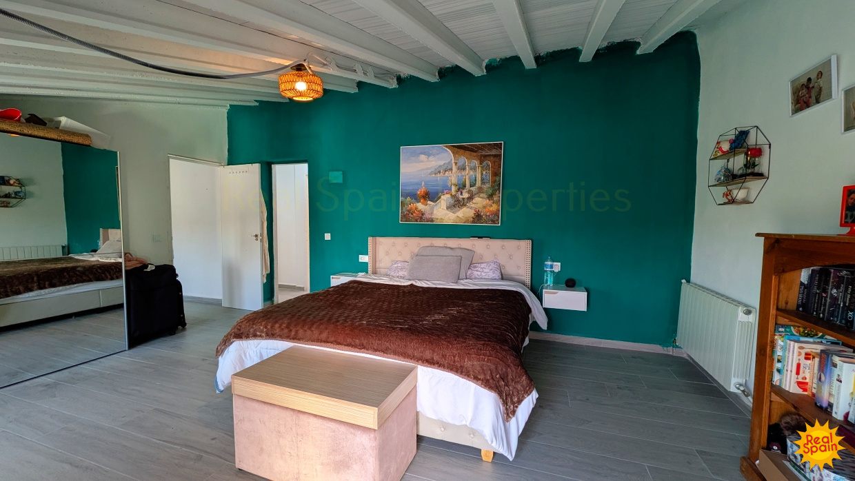 Large bedroom at Cortijo Salud with turquoise wall, bed and doorway